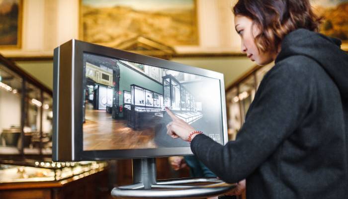 A woman in the museum uses the touchscreen monitor electronic guide, the concept of modern education